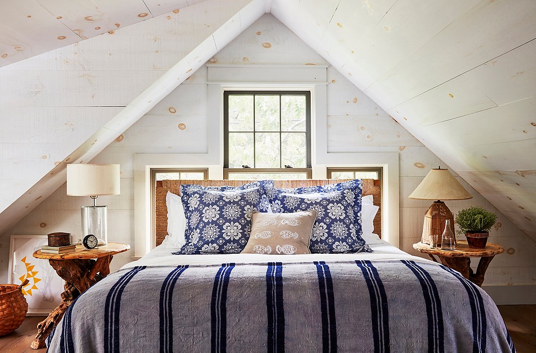 Nightstands found at the Brimfield Antique Show flank a woven-rush headboard in a cozy guest bedroom. The pine-clad walls were washed with milk paint, which âadded a great textural quality,â says T.R.