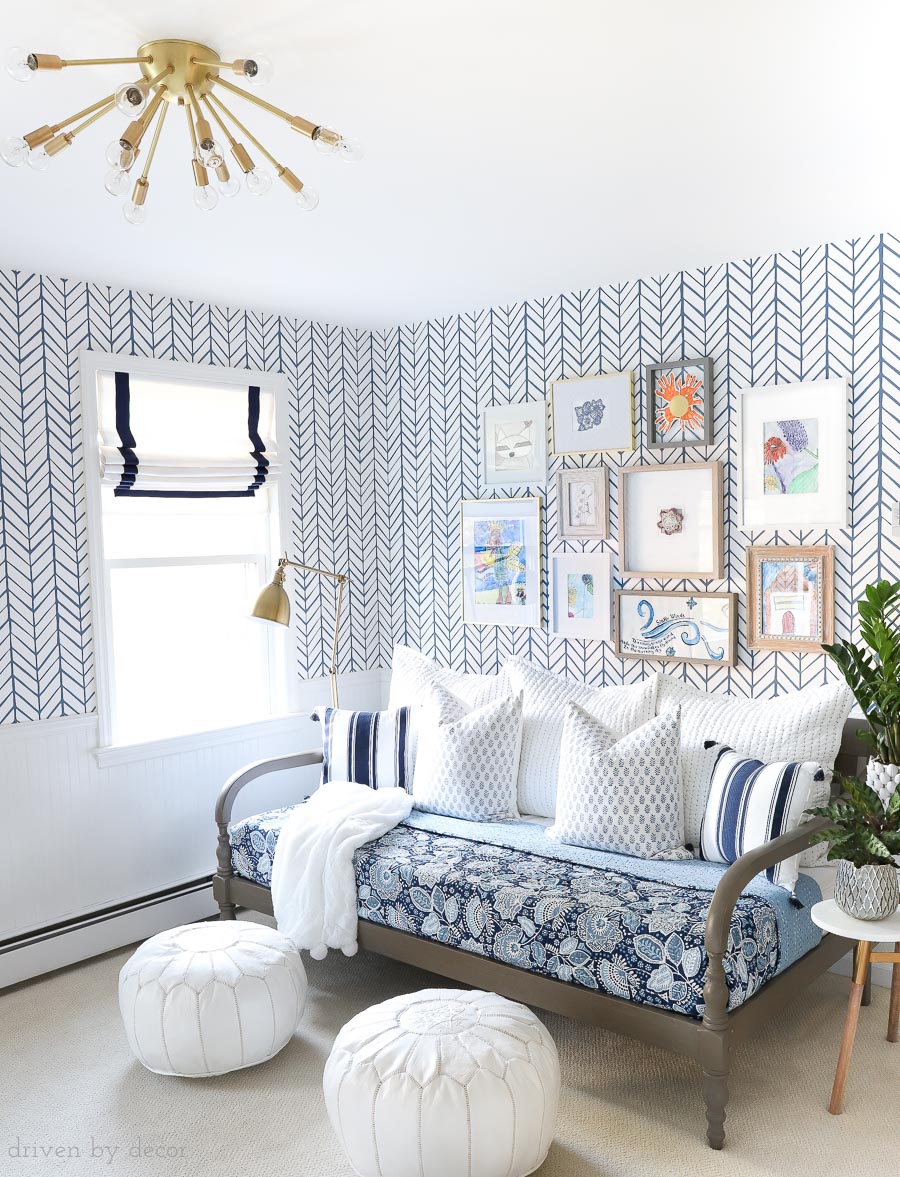 Fun bonus room space with daybed for lounging (that will also be used as a guest bed), kids art gallery wall, blue and white wallpaper and bedding, Moroccan poufs, Roman shades, and brass sputnik light fixture!