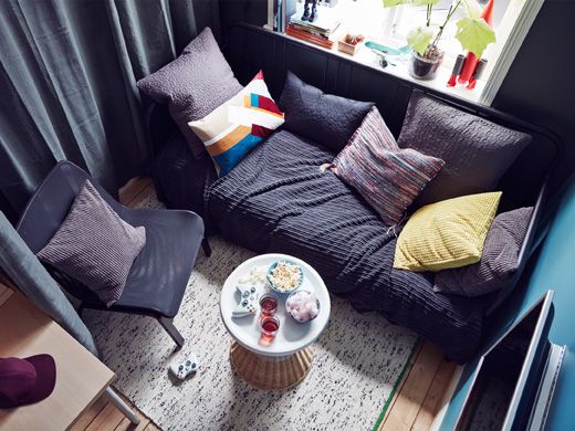 An aerial view of a teen room lounge area with a day-bed sofa, an easy chair and a bedside table