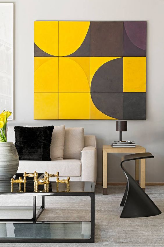 Close up of yellow and grey painting, with a pale wood side table and a neutral sofa. Black coffee table; gold accents to play up the yellow.